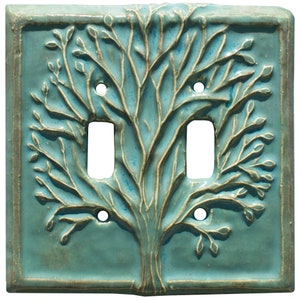 May include: A light blue ceramic double light switch cover with a raised tree design.