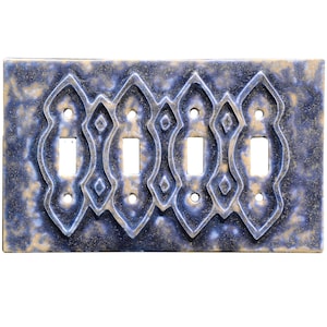 May include: A decorative four-gang light switch plate. The plate has a blue and gold mottled finish with an ornate, raised design. The switch openings are rectangular, and the plate has screw holes for mounting.