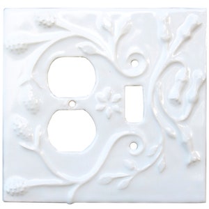 Pode incluir: Interruptor de luz e tomada de porcelana branca com um design floral ornamentado.