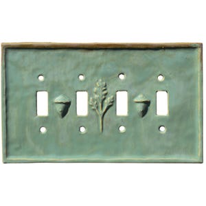 May include: A teal ceramic light switch plate with four switch openings. The plate features embossed acorns and a leaf design. The edges have a brown trim. The plate has a rustic, handmade appearance.