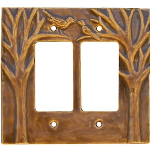 Peut inclure: Un cache-interrupteur double de couleur bronze avec un motif inspiré de la nature. Le cache-interrupteur présente un relief de deux oiseaux perchés sur une branche d'arbre, avec des branches d'arbres encadrant les ouvertures des interrupteurs. Le couvercle comporte quatre trous de vis.