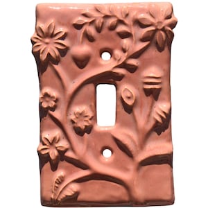 May include: A decorative, ceramic light switch cover in a warm, reddish-brown hue. The cover features an embossed floral design with flowers, leaves, and vines. It has a rectangular opening for the switch and two holes for mounting.