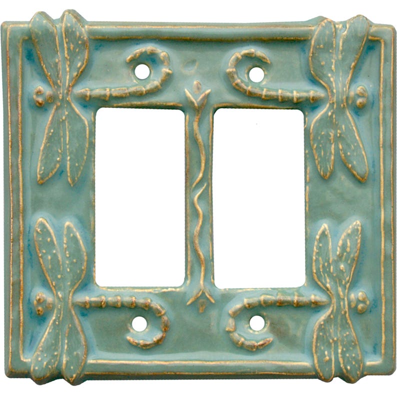 Może przedstawiać: Podw&oacute;jny przełącznik światła ceramiczny w jasnoniebieskim kolorze z wzorem ważki. Ważka jest w kolorze złotym, a przełącznik ma fakturowaną powierzchnię.