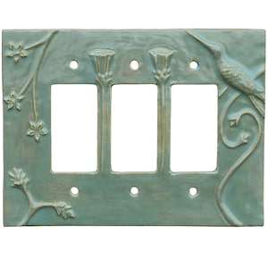以下が含まれることがあります： ターコイズ色のセラミック製トリプルライトスイッチカバー。ハチドリと花のレリーフデザイン。スイッチ用の長方形の開口部が3つあり、取り付け用の小さな穴がいくつかあります。