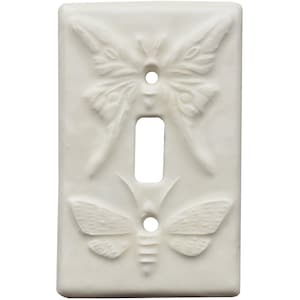 May include: Off-white single light switch cover with a raised relief design of two moths. The top moth has its wings spread, and the bottom moth has its wings closed. The cover is rectangular with a single toggle switch opening.