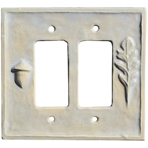 Peut inclure: Plaque de prise double en céramique blanc cassé avec des motifs de glands et de feuilles en relief. La plaque rectangulaire comporte deux ouvertures pour interrupteurs et des trous de vis. La plaque décorative a une esthétique rustique et naturelle.