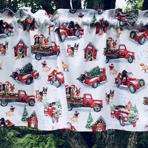 a festive window valance with a repeating pattern of red trucks carrying Christmas trees and Santa hats