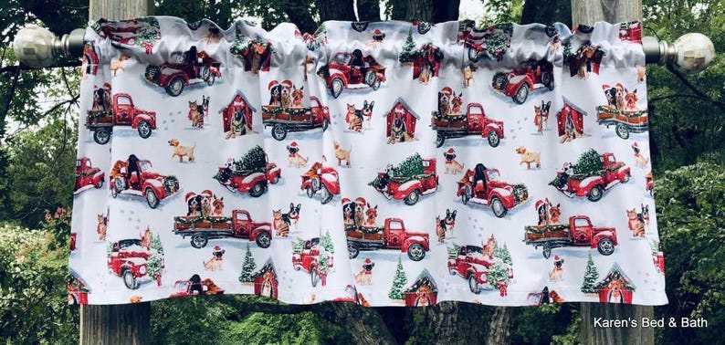 a festive window valance with a repeating pattern of red trucks carrying Christmas trees and Santa hats