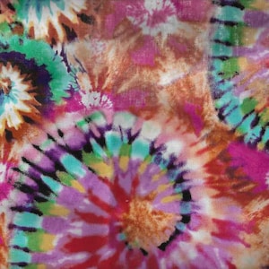 K&ouml;nnte beinhalten: Ein farbenfroher Batikstoff mit einem wirbelnden Muster in den Farben Rosa, Lila, Blau, Gr&uuml;n und Braun.