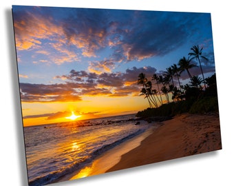 Könnte beinhalten: Ein lebendiger Sonnenuntergang über einem tropischen Strand mit Palmen, die sich vor dem orangefarbenen und blauen Himmel abzeichnen. Die Wellen des Ozeans schlagen an den sandigen Ufer.