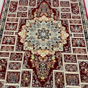 May include: A detailed, rectangular rug with a central medallion and repeating floral patterns. The rug features a deep red background with cream and blue accents. The design includes floral motifs and geometric borders, creating a traditional aesthetic.