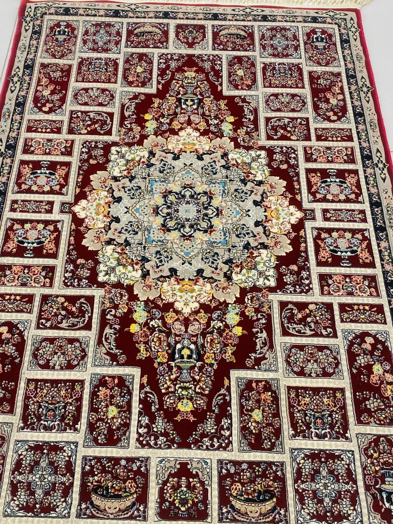 May include: A detailed, rectangular rug with a central medallion and repeating floral patterns. The rug features a deep red background with cream and blue accents. The design includes intricate floral and geometric elements, creating a classic, ornate look.