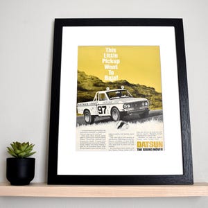 May include: A vintage Datsun pickup truck drives through a desert landscape. The truck is white with black accents and the number "97" on the side. The text "This little pickup went to Baja!" is printed above the truck. The text "Datsun The Sound Mover" is printed below the truck.