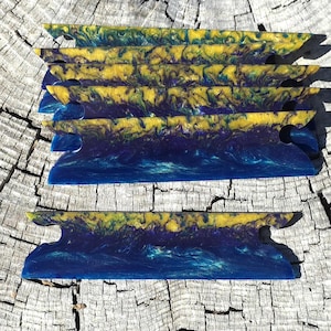 May include: A set of six flat, rectangular resin dividers featuring a marbled pattern of deep blue, dark purple, and bright yellow. Each divider has a notched design on both sides, creating a distinct shape with a smooth, glossy finish.