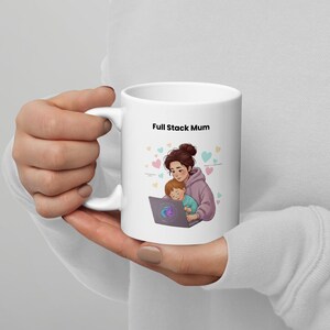 Op de afbeelding: Witte keramische mok met de tekst "Full Stack Mum". De mok heeft een illustratie van een moeder en kind die een laptop gebruiken, omringd door hartvormen. Het ontwerp bevat paarse, blauwe en roze kleuren.
