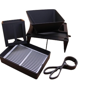 Pode incluir: Um conjunto de churrasco preto com vários componentes. Inclui uma bandeja quadrada com uma grelha de metal, um recipiente retangular com a palavra "Front", uma peça em forma de funil e um par de pinças.
