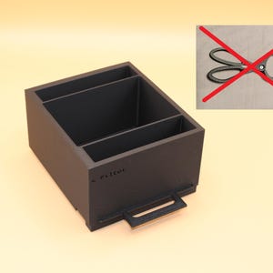 Op de afbeelding: Een donkergrijze bureau-organizer met drie compartimenten en een handvat. De organizer is gemaakt van een stevig materiaal en heeft het woord "s. Ritter" op de zijkant gedrukt. De achtergrond is lichtbeige.