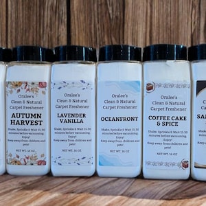 May include: A collection of eight white plastic bottles with black lids, labeled as "Oralee's Clean & Natural Carpet Freshener." The scents include Fresh Linen, Apple Pie, Autumn Harvest, Lavender Vanilla, Oceanfront, Coffee Cake & Spice, Sandalwood & Amber, and Mountain Rain. Each bottle contains 16 oz.