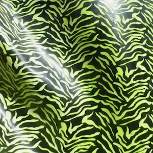 May include: A close-up of a fabric with a black and green zebra print pattern. The fabric has a shiny, glossy finish.