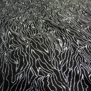 May include: Black fabric with a silver metallic pattern of wavy lines. The fabric has a textured surface.