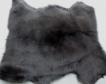 May include: A dark gray fur pelt with a soft, fluffy texture. The fur is thick and dense, and the pelt is large and flat.