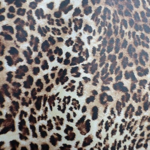 May include: A close-up of a brown and beige fabric with a leopard print pattern.