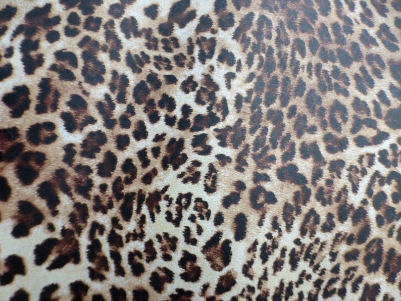May include: A close-up of a brown and beige fabric with a leopard print pattern.