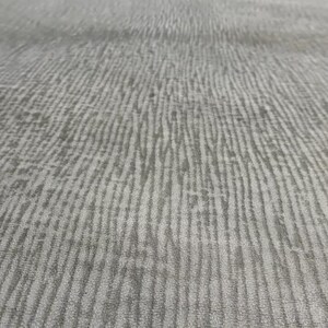 May include: Close-up of a grey textured fabric with a subtle striped pattern.