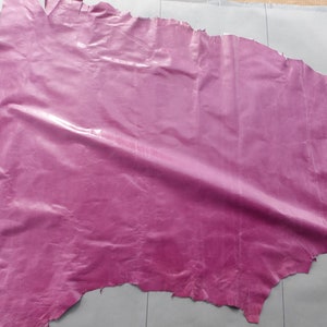 May include: A large piece of pink leather with a glossy finish. The leather is wrinkled and has a slightly uneven texture.