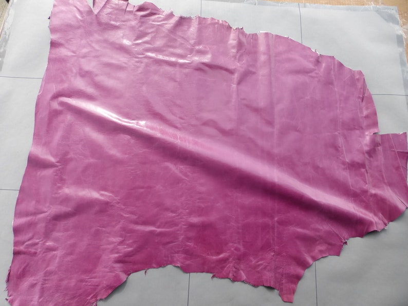May include: A large piece of pink leather with a glossy finish. The leather is wrinkled and has a slightly uneven texture.