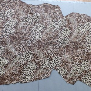 May include: A beige and brown leopard print fabric with a textured surface.