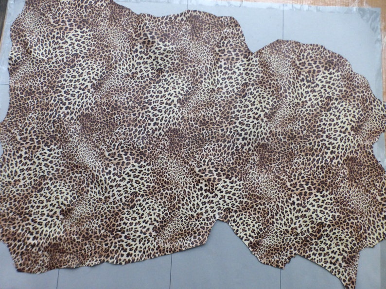 May include: A beige and brown leopard print fabric with a textured surface.