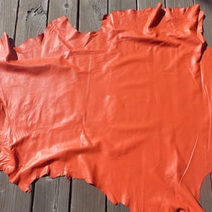 May include: A large piece of orange leather, folded and laid out on a wooden surface.