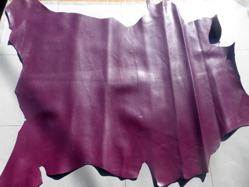 May include: A piece of purple leather with a smooth, shiny finish. The leather is folded and has a slightly irregular shape.