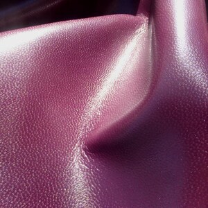 May include: Close-up of a textured, deep purple fabric with a subtle shimmer. The fabric has a soft, luxurious feel.