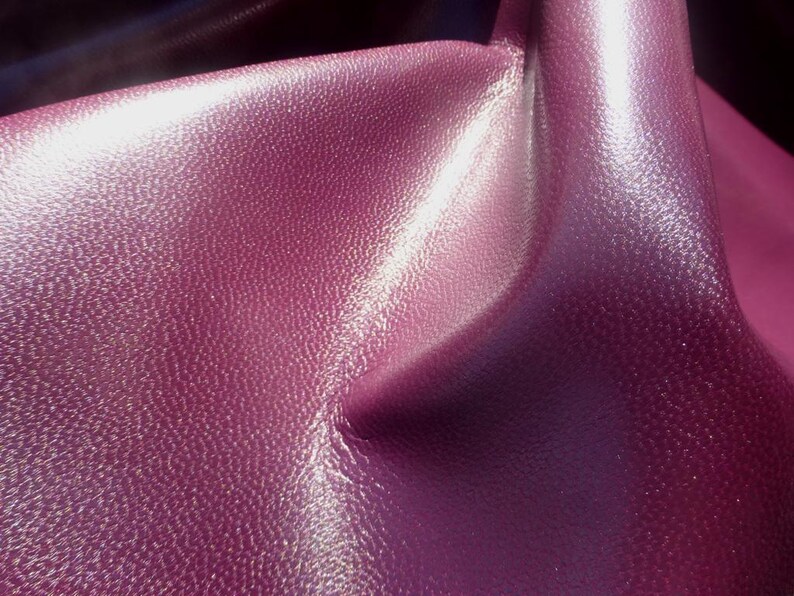 May include: Close-up of a textured, deep purple fabric with a subtle shimmer. The fabric has a soft, luxurious feel.