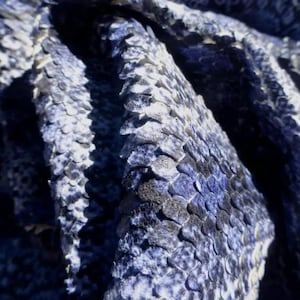 Op de afbeelding: Close-up van blauwe en witte gepatenteerde slangenleer. De schubben zijn zichtbaar en getextureerd.