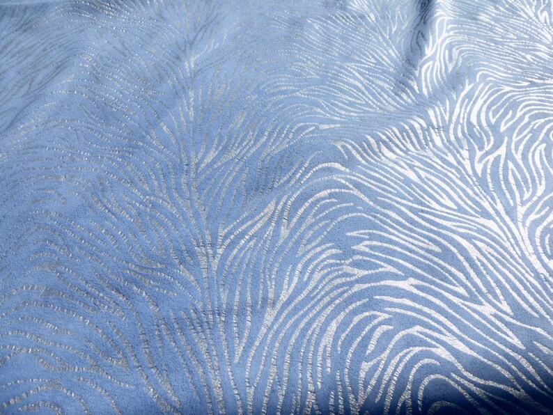 Op de afbeelding: Een close-up van een blauwe stof met een zilveren zebraprint.