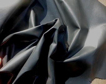 May include: A close-up of a dark gray leather fabric with a smooth, shiny finish. The fabric is folded and draped, showing its texture and drape.
