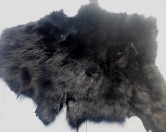 May include: A black sheepskin rug with a soft, fluffy texture.