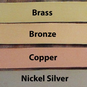 Pu&ograve; includere: Quattro campioni di metallo in diverse finiture: ottone, bronzo, rame e argento nichelato. I campioni sono disposti verticalmente, con l'ottone in alto e l'argento nichelato in basso.
