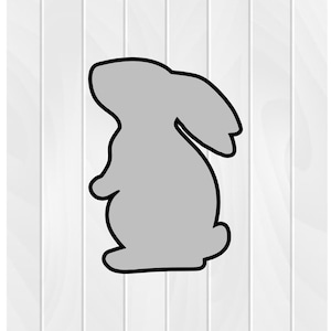 May include: A gray silhouette of a rabbit standing on a white wood background.