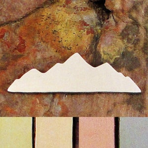May include: White metal mountain range silhouette charm. The charm is a simple design with a rounded top and a flat bottom. The charm is shown against a brown background.