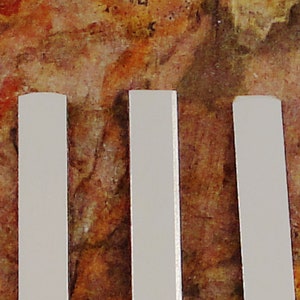 May include: Three white rectangular wooden blocks standing upright against a brown and orange textured background.