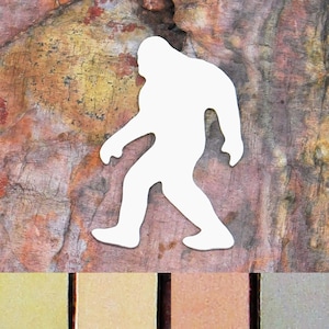 May include: White silhouette of Bigfoot walking on a brown, textured background. The background has shades of yellow, orange, and red.