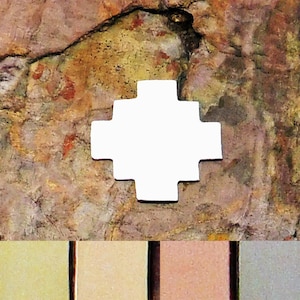 May include: A white ceramic cross with a geometric design. The cross is on a brown, textured background.