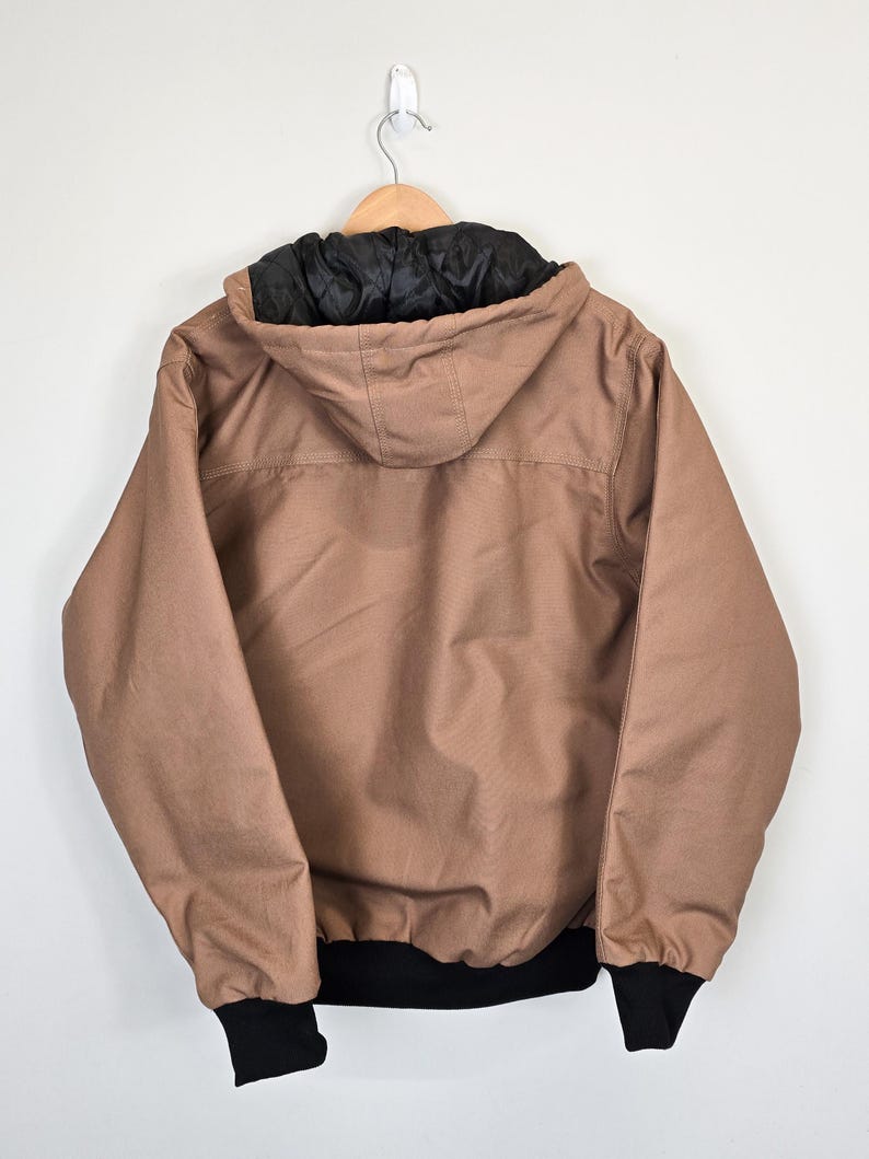 May include: A brown hooded jacket with a black lining and black cuffs. The jacket has a zipper closure and two pockets.