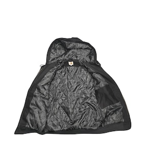 May include: Black hooded jacket with a zipper closure and a quilted lining. The jacket has a pocket on the inside.