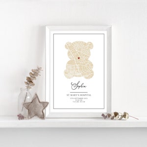 May include: A white framed print featuring a beige teddy bear made from a city map. The bear has a red heart in the centre. The print includes the name "Sophia", "St. Mary's Hospital", the date "12th September 2023", the time "10:44 AM", the weight "3.44 KG", and the length "52 CM".