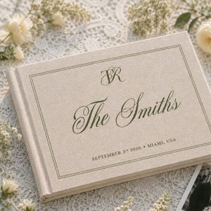 May include: A rectangular, beige linen-covered photo album featuring a dark green border and custom text. The cover displays the monogram TR, the name The Smiths, and the date SEPTEMBER 3rd 2026 • MIAMI, USA in a dark green serif and script font.